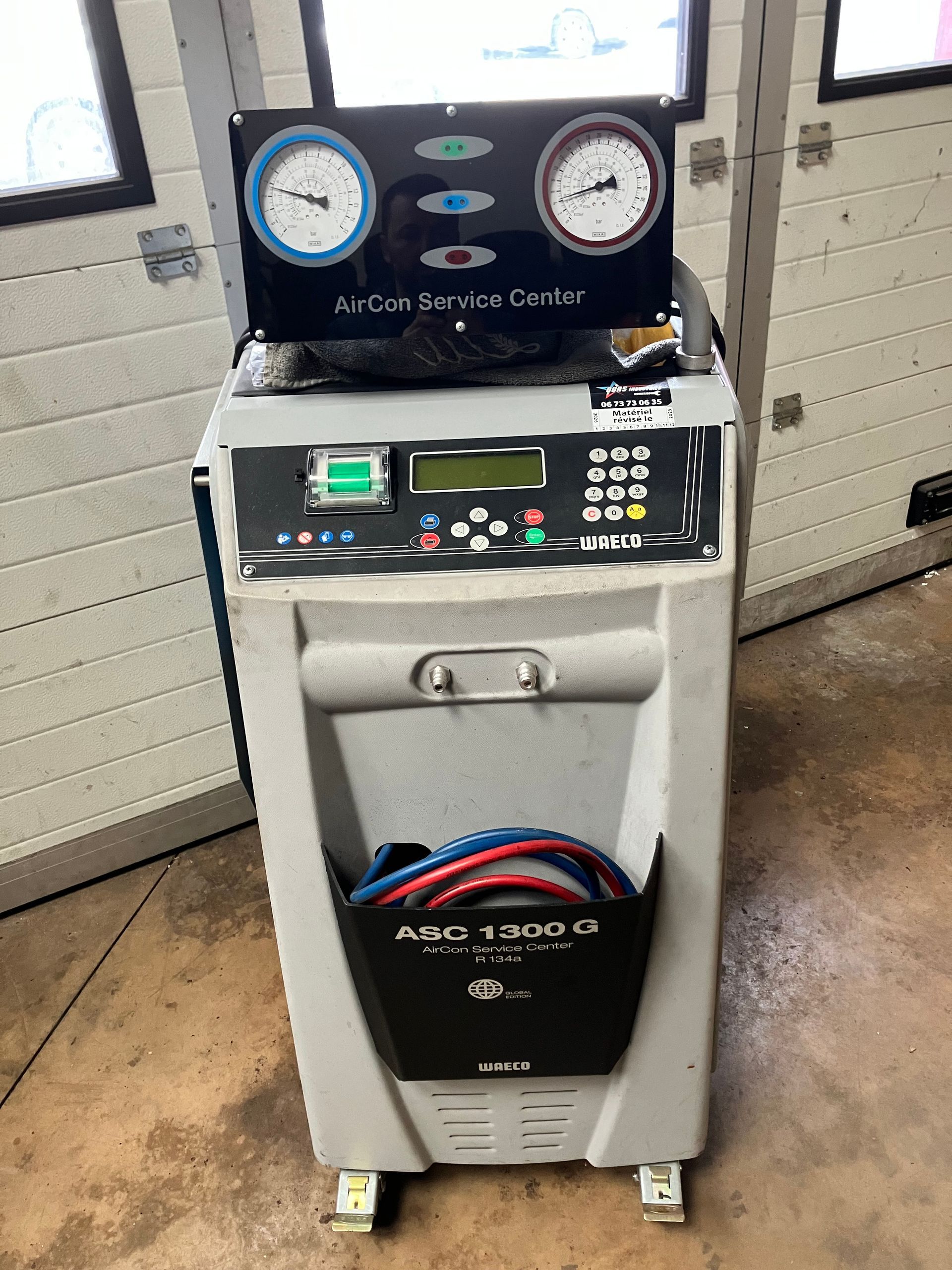 Machine pour charger les systèmes de climatisation avec manomètres, panneau de commande et rangement pour tuyau.