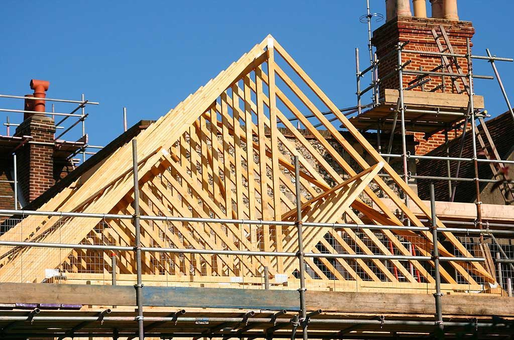 Charpente en bois en construction sur une maison, se détachant sur un ciel bleu