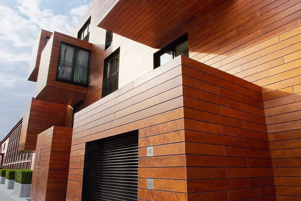 Bâtiment moderne en briques avec des éléments en bois et une porte de garage sombre sous un toit en pente
