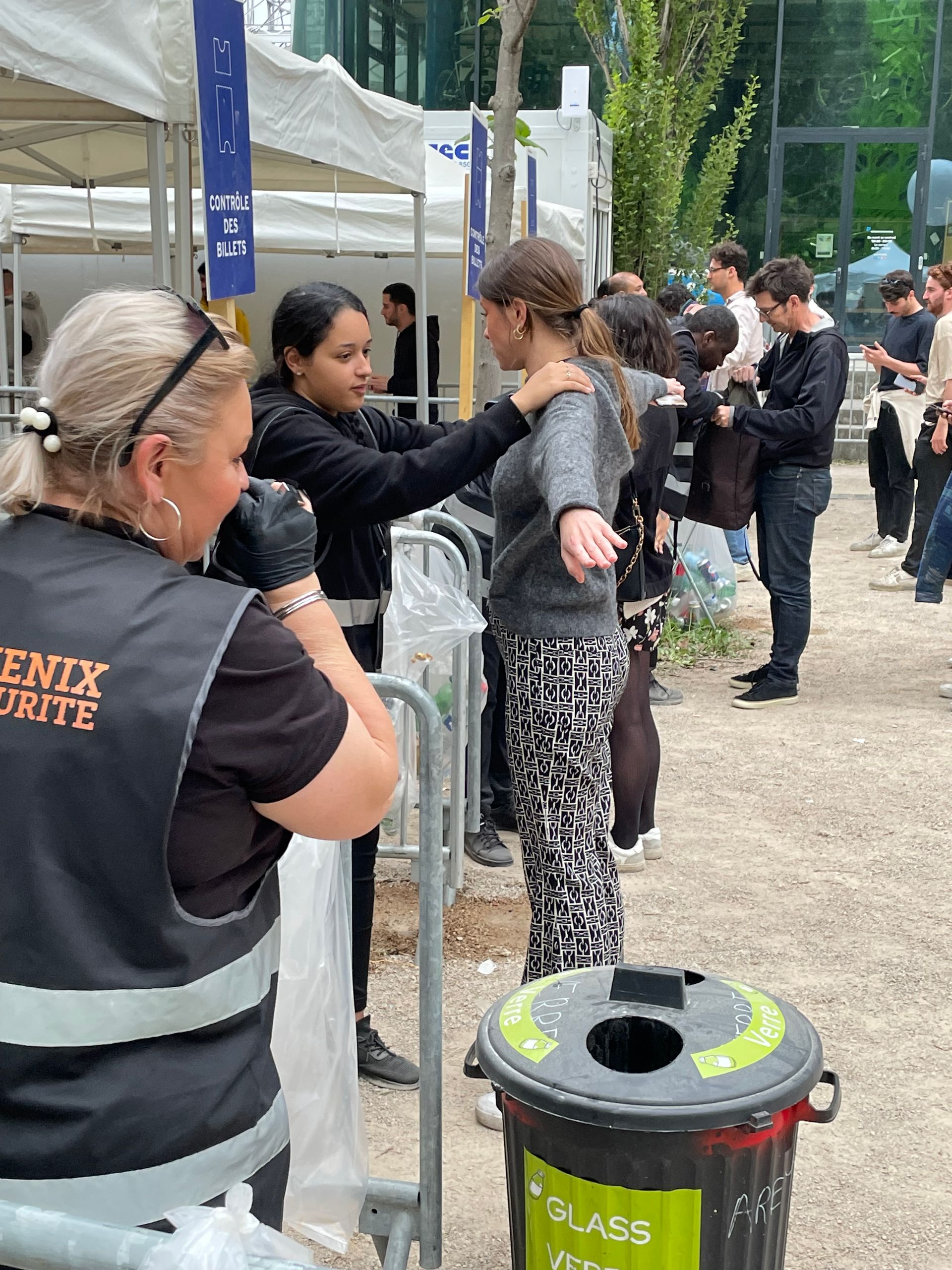 Agent de sécurité de dos au premier plan et fouille d'une personne au second plan