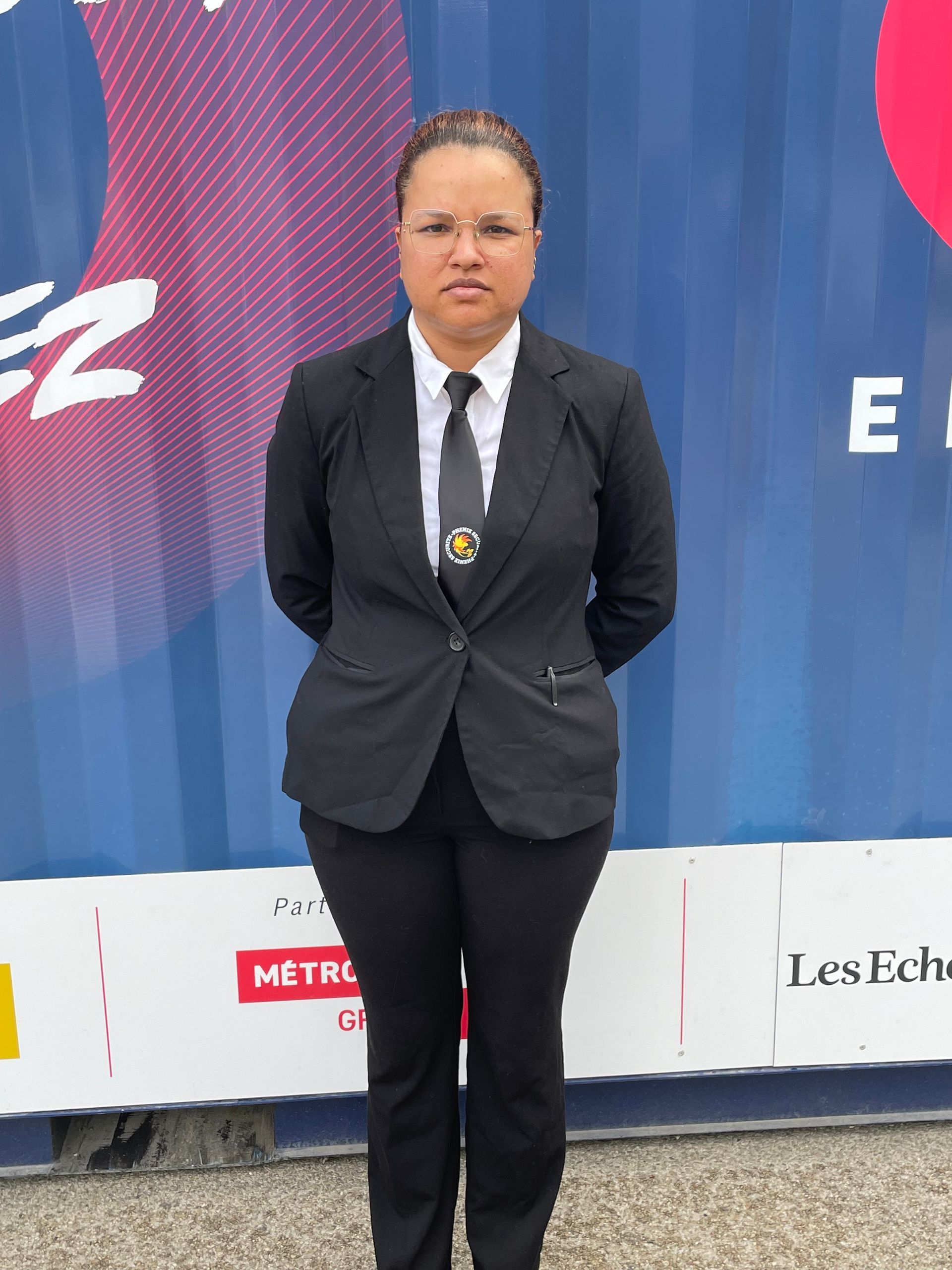 Agent de sécurité en costume noir posant les bras croisés derrière le dos