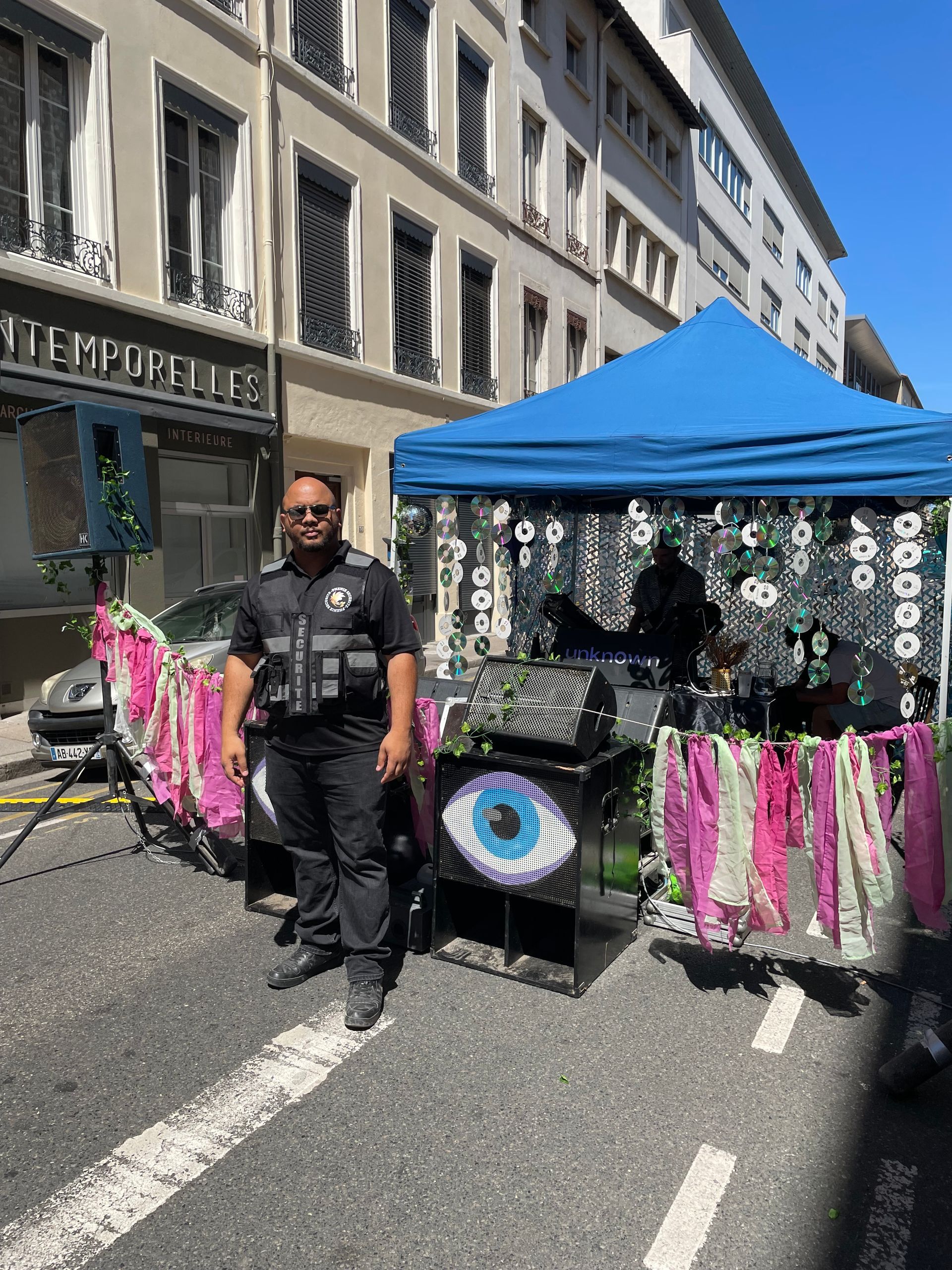 Agent de sécurité devant un stand de festival avec un voile bleu sur le toit