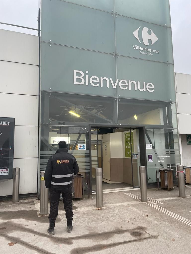Agent de sécurité devant devanture où il y a marqué Bienvenue
