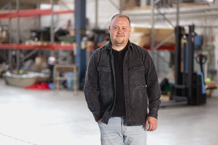 Mann in schwarzem Blazer und weißem Hemd, verschwommener Hintergrund.