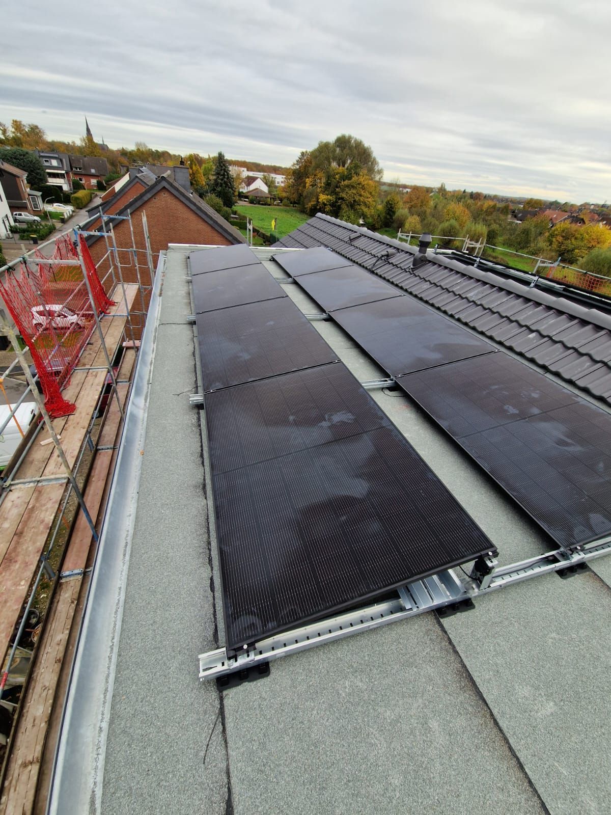 Auf einem Dach installierte Solarpaneele. Graue und schwarze Paneele vor bedecktem Himmel.