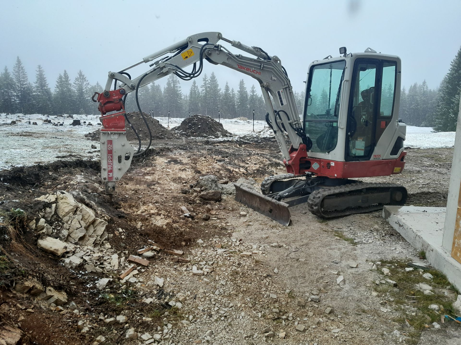 Ein Kettenbagger arbeitet auf einer Baustelle mit steinigem Untergrund.