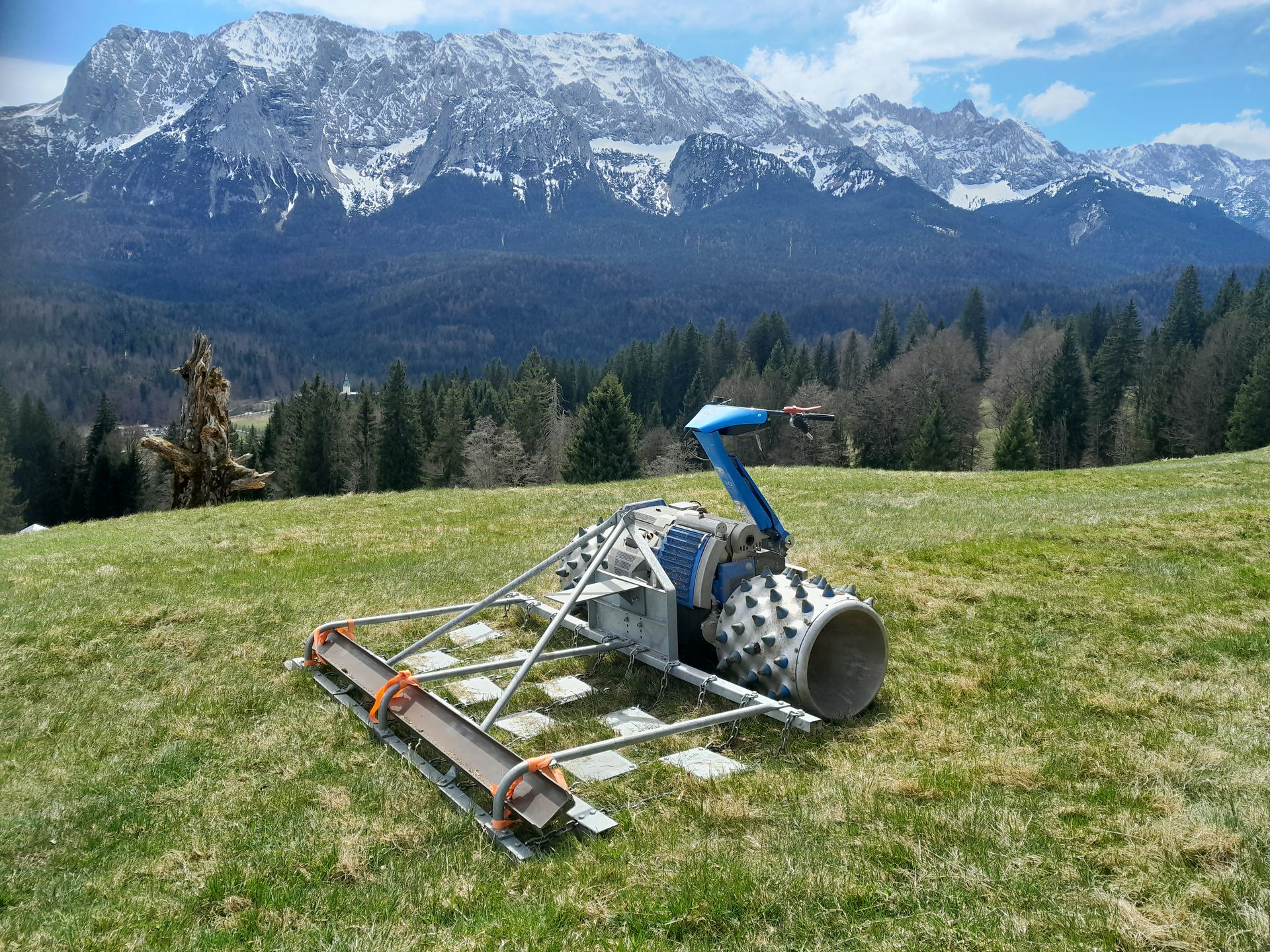 Spezial-Böschungsmäher bei der Landschaftspflege auf einer Bergwiese vor Gebirgskulisse.