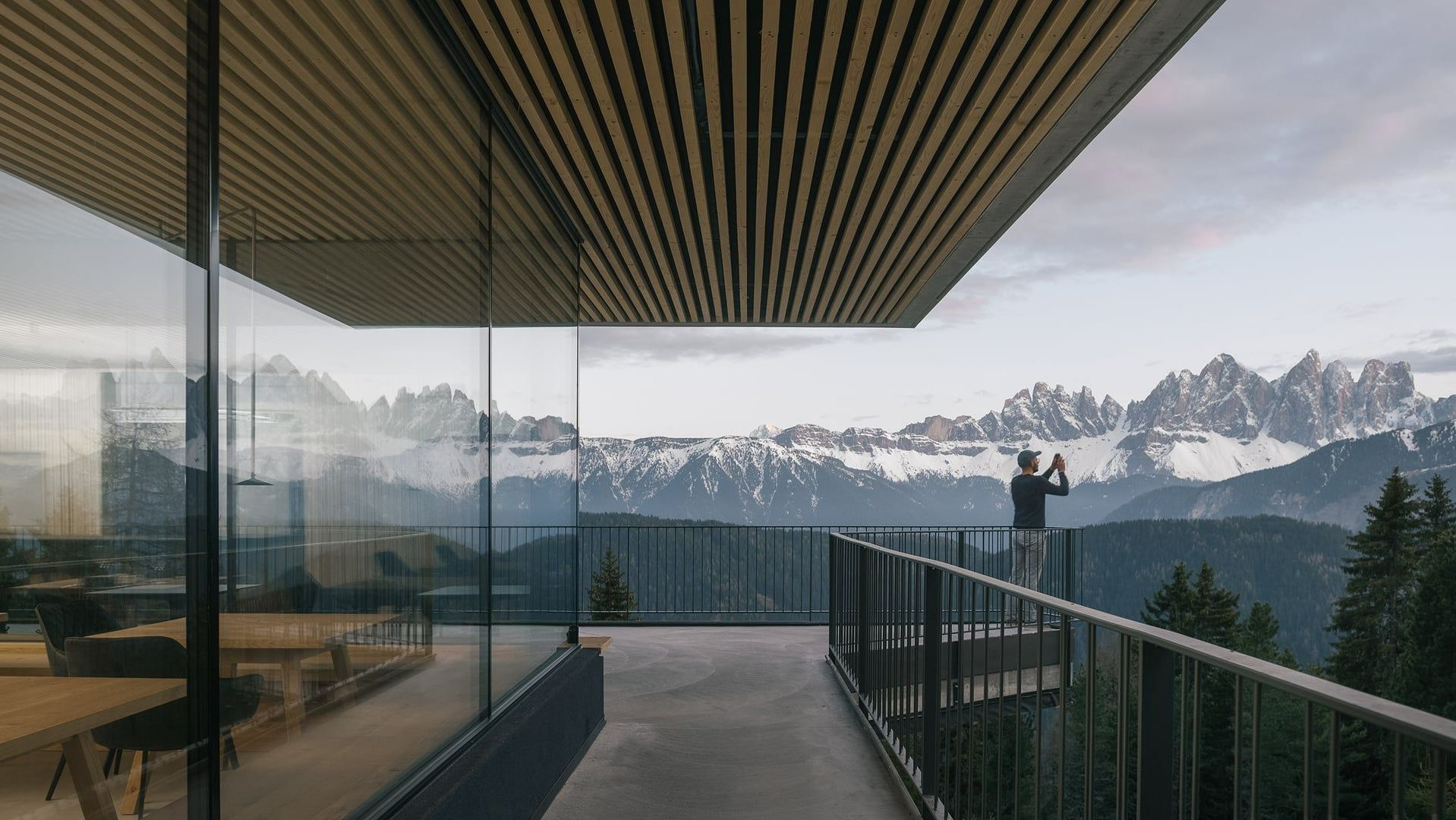 Homme sur un balcon prenant en photo des montagnes