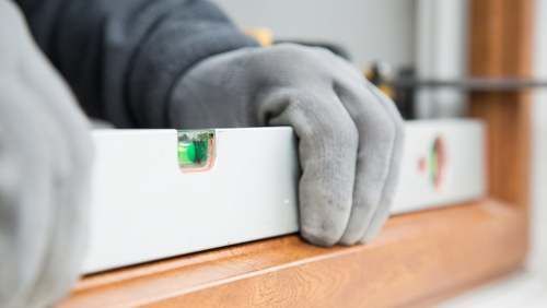 Des mains dans gants tenant un niveau