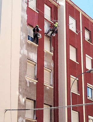 Un grupo de personas está pintando el costado de un edificio.