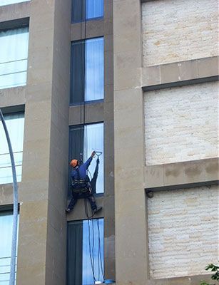 Un hombre está limpiando las ventanas de un edificio alto.