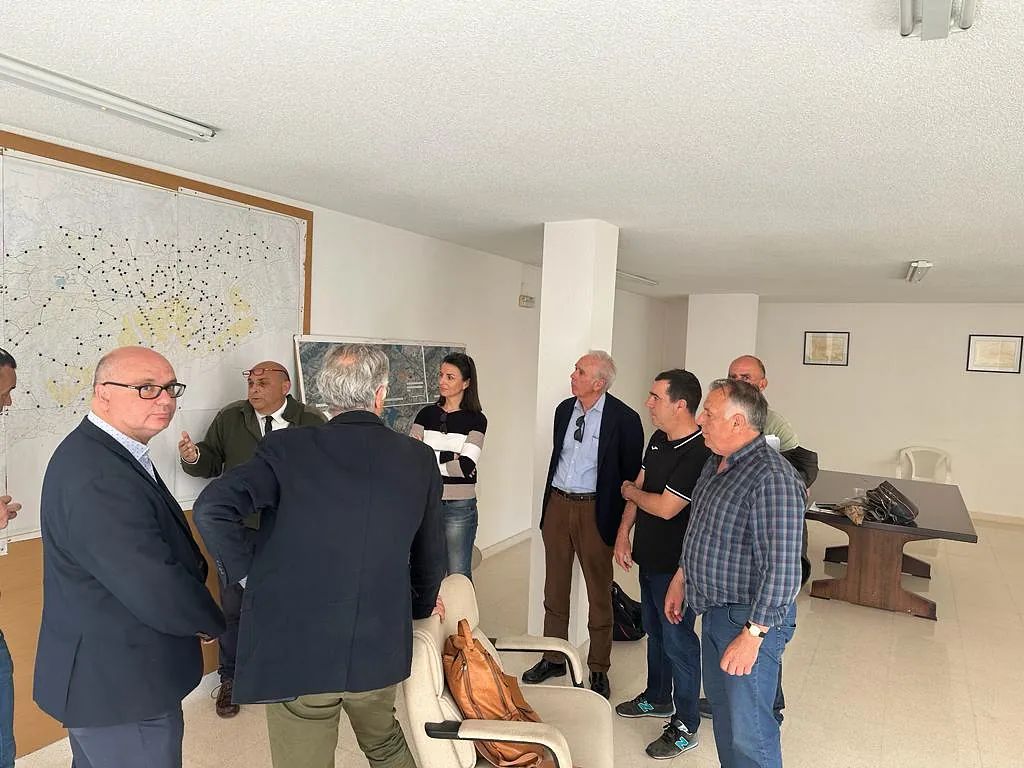 Un grupo de personas están de pie en una habitación hablando entre sí.