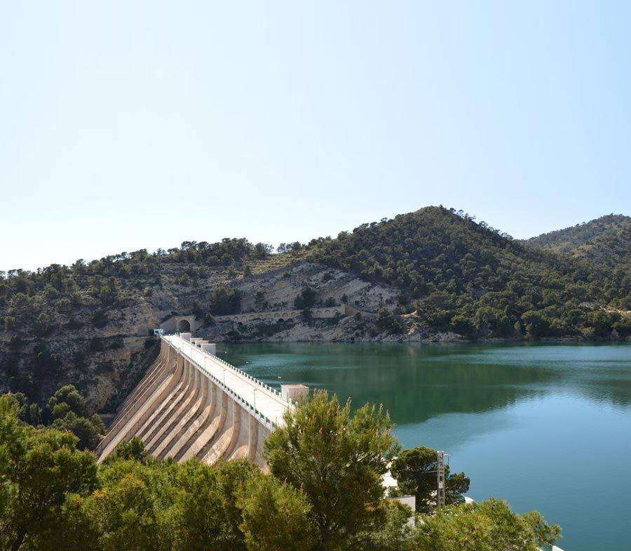 Una presa sobre un lago rodeado de árboles y montañas