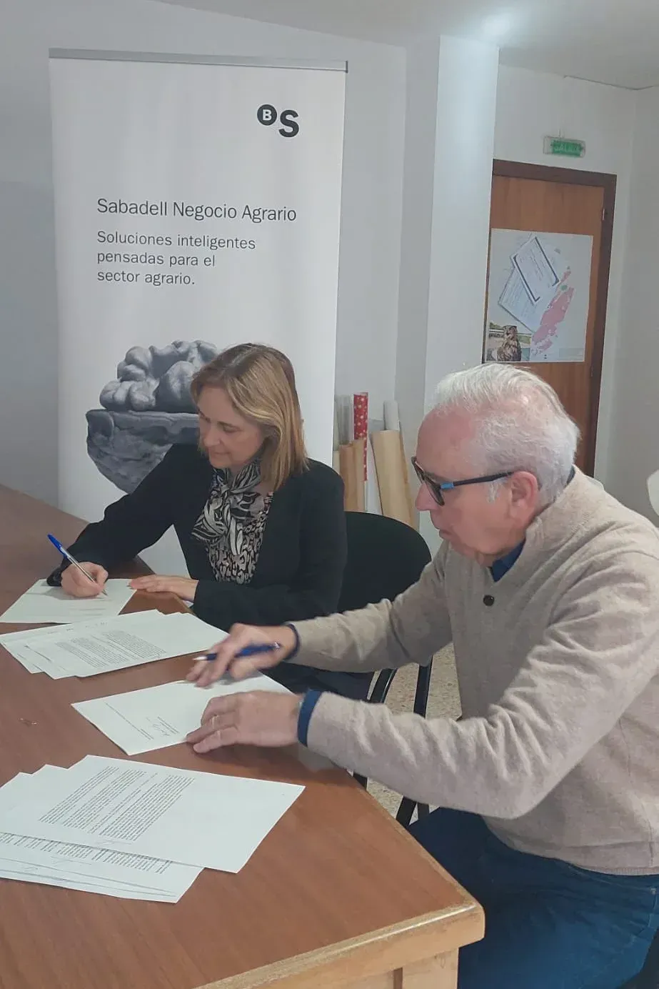 Un hombre y una mujer están sentados en una mesa escribiendo en papeles.