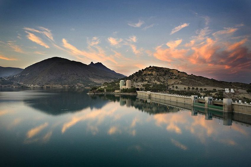 Un lago con montañas al fondo y un castillo en primer plano.