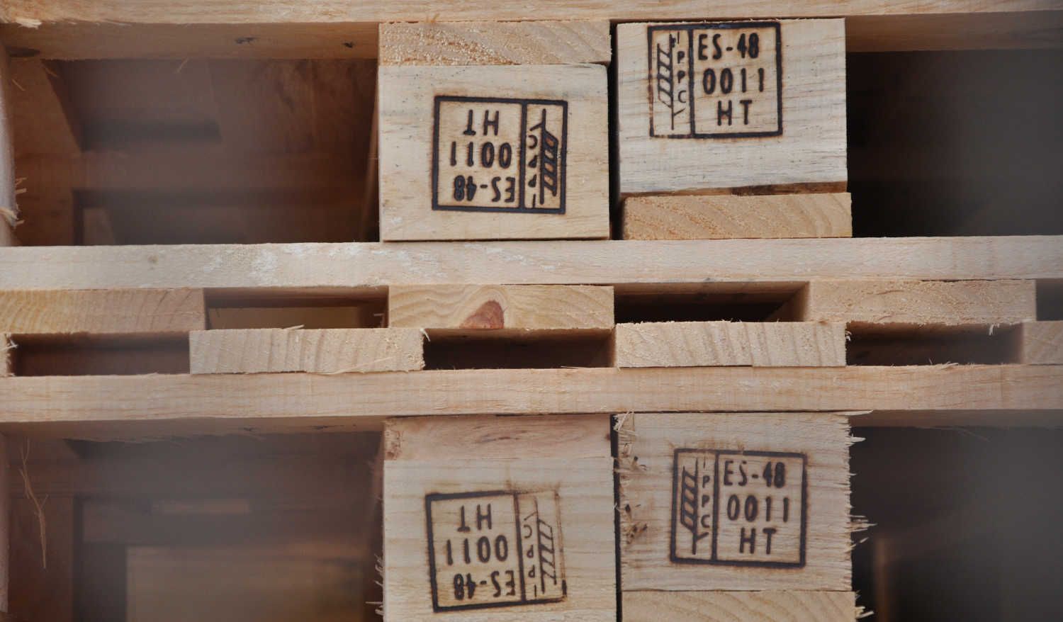 Montones de coloridos palets de plástico al aire libre contra un cielo gris.