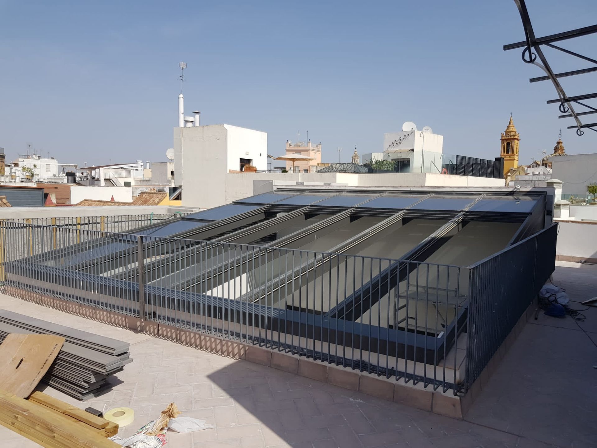 Azotea con grandes paneles solares inclinados en un edificio urbano plano bajo un cielo despejado.