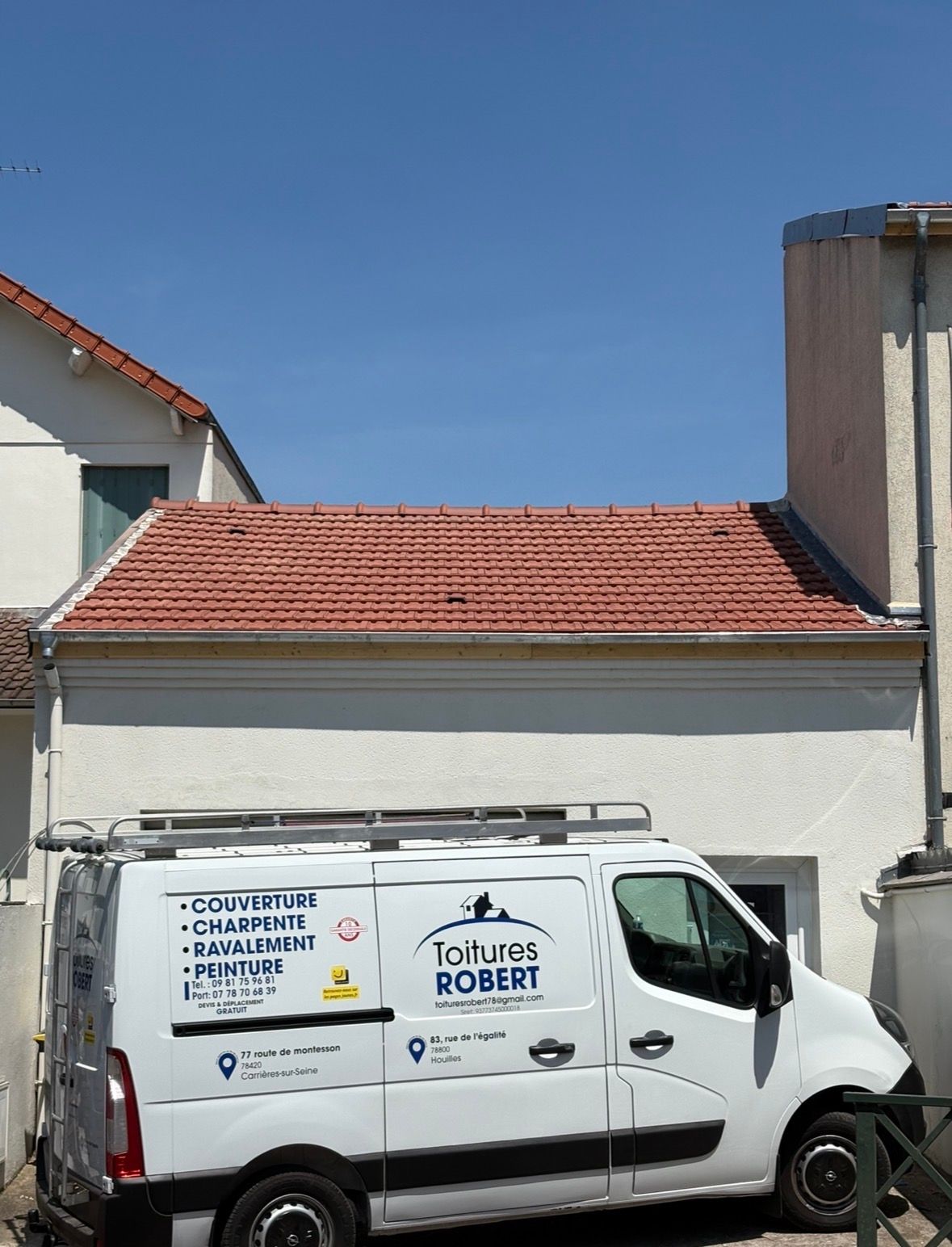 Une camionnette blanche portant l'inscription Toitures ROBERT est garée devant un bâtiment au toit de tuiles rouges.