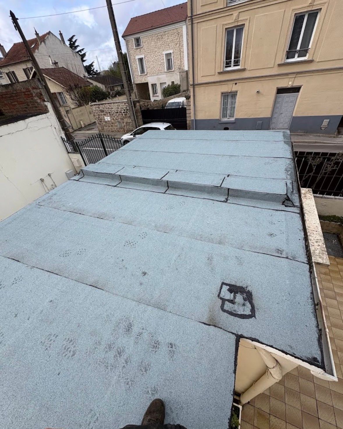 Vue en plongée d'un toit plat en membrane gris clair avec une partie surélevée