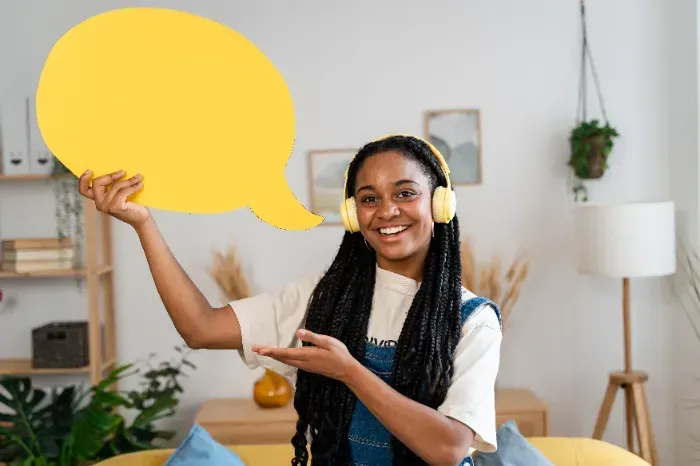 Uma mulher usando fones de ouvido está segurando um balão de fala amarelo.