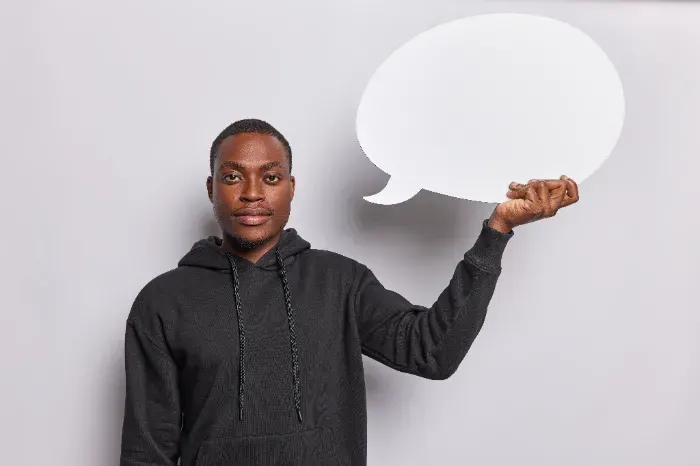 Um jovem está segurando um balão de fala na mão.