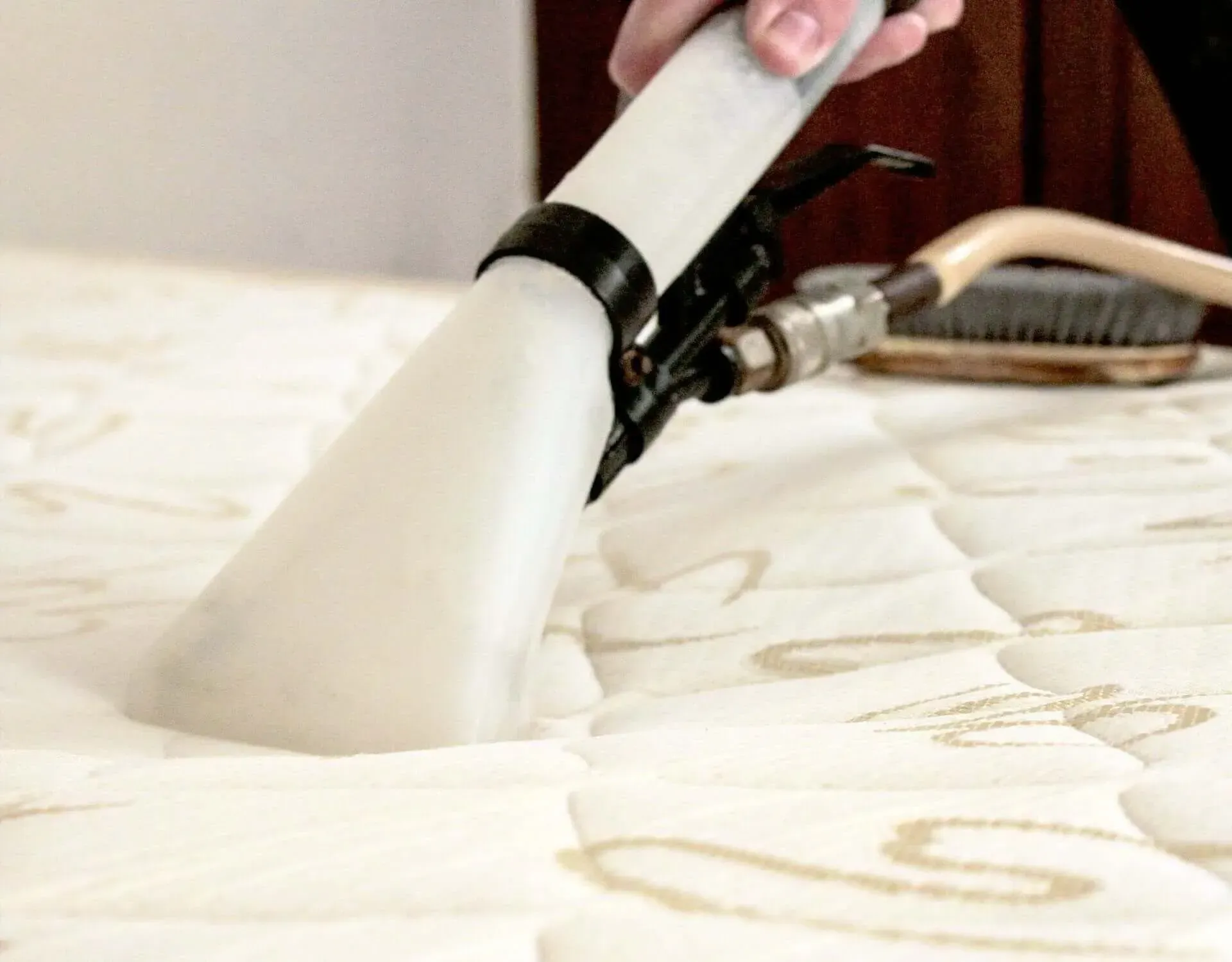 Uma pessoa está a limpar um colchão com um aspirador de pó