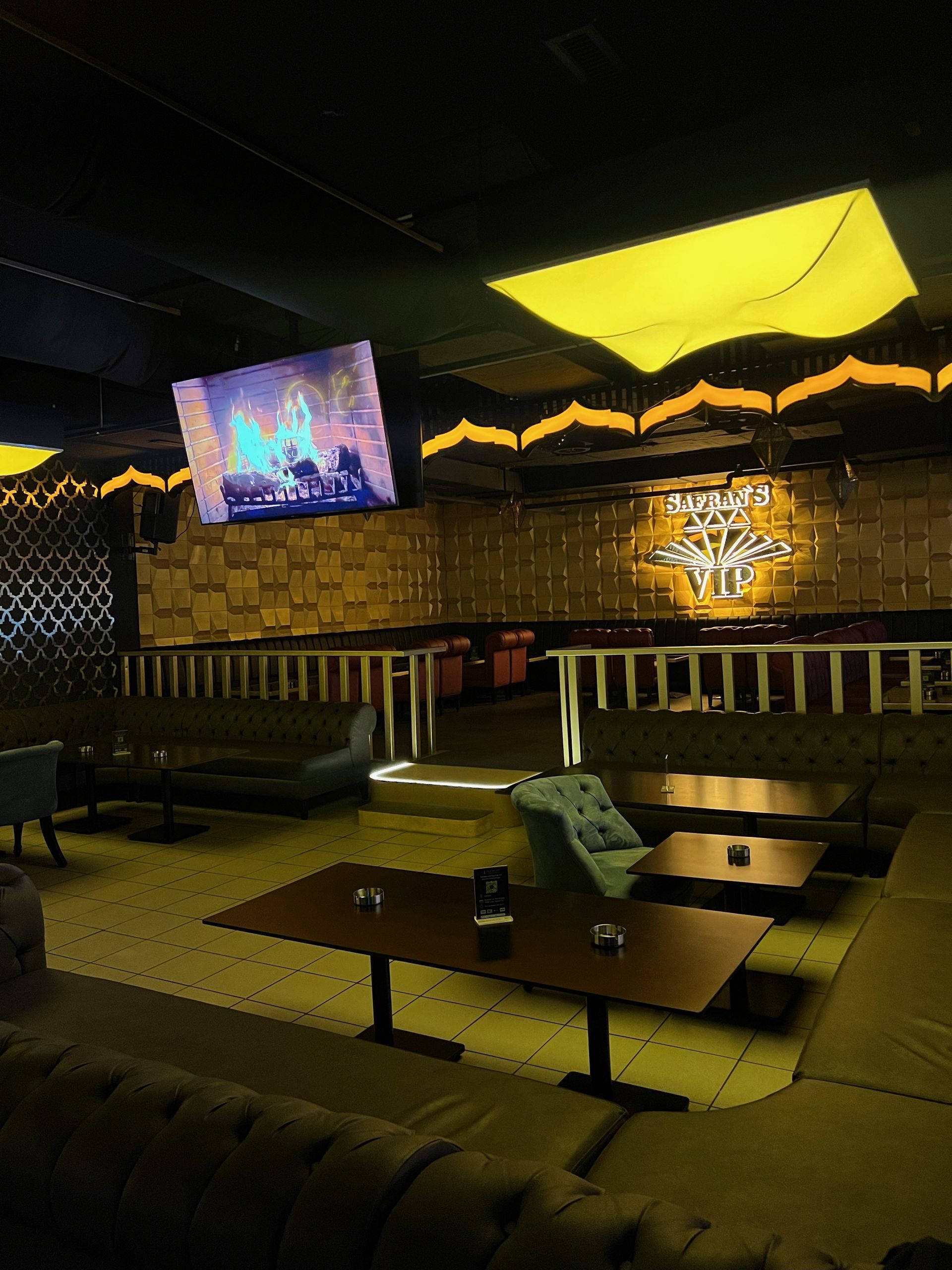 Ein großer Raum mit Tischen und Stühlen und einem Fernseher an der Decke.