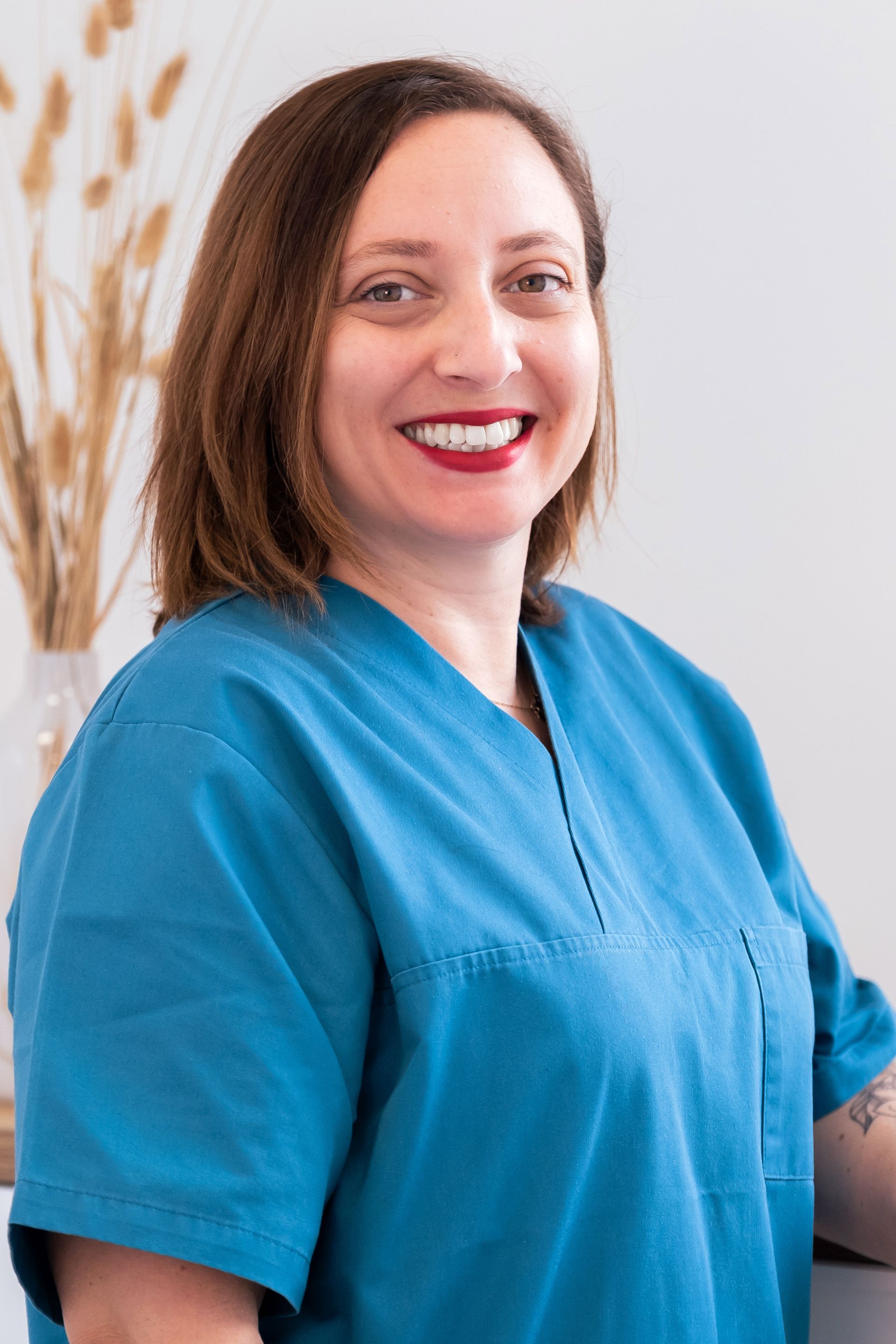 Deux soignants en blouse turquoise se tiennent côte à côte dans un environnement médical.