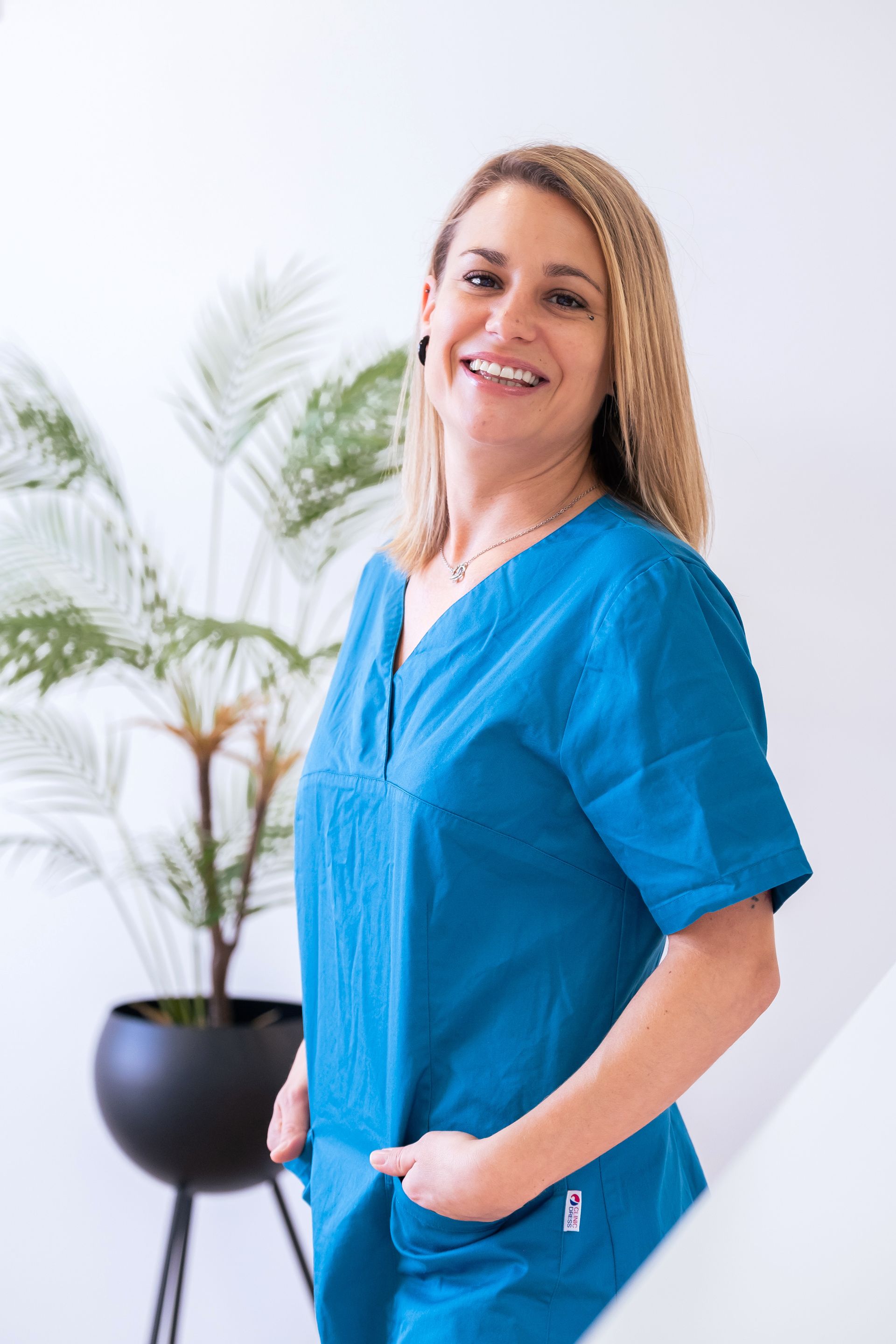 Deux femmes en blouse turquoise sourient, à l'intérieur d'un cercle turquoise.
