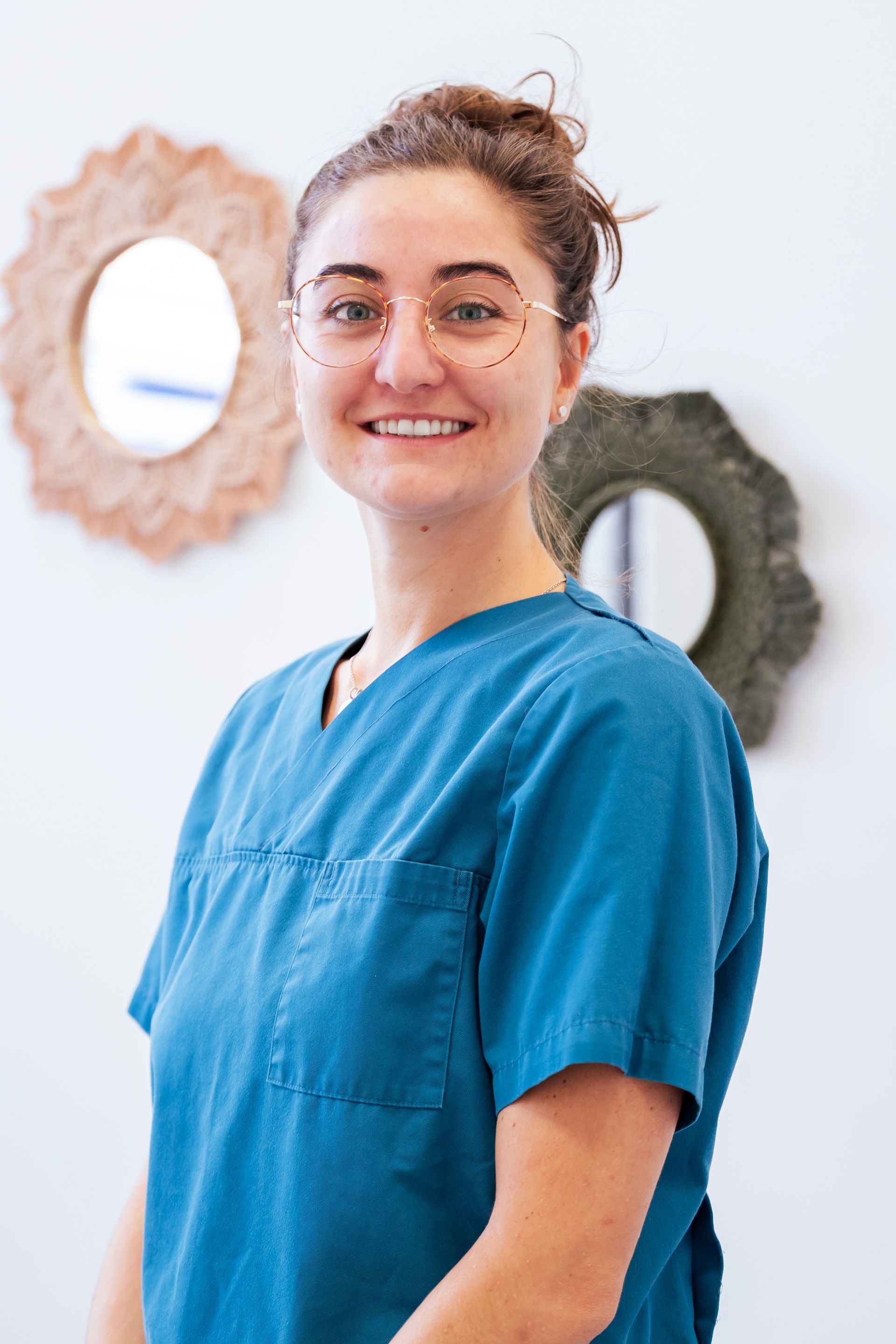 Deux soignants en blouse turquoise se tiennent côte à côte dans un environnement médical.