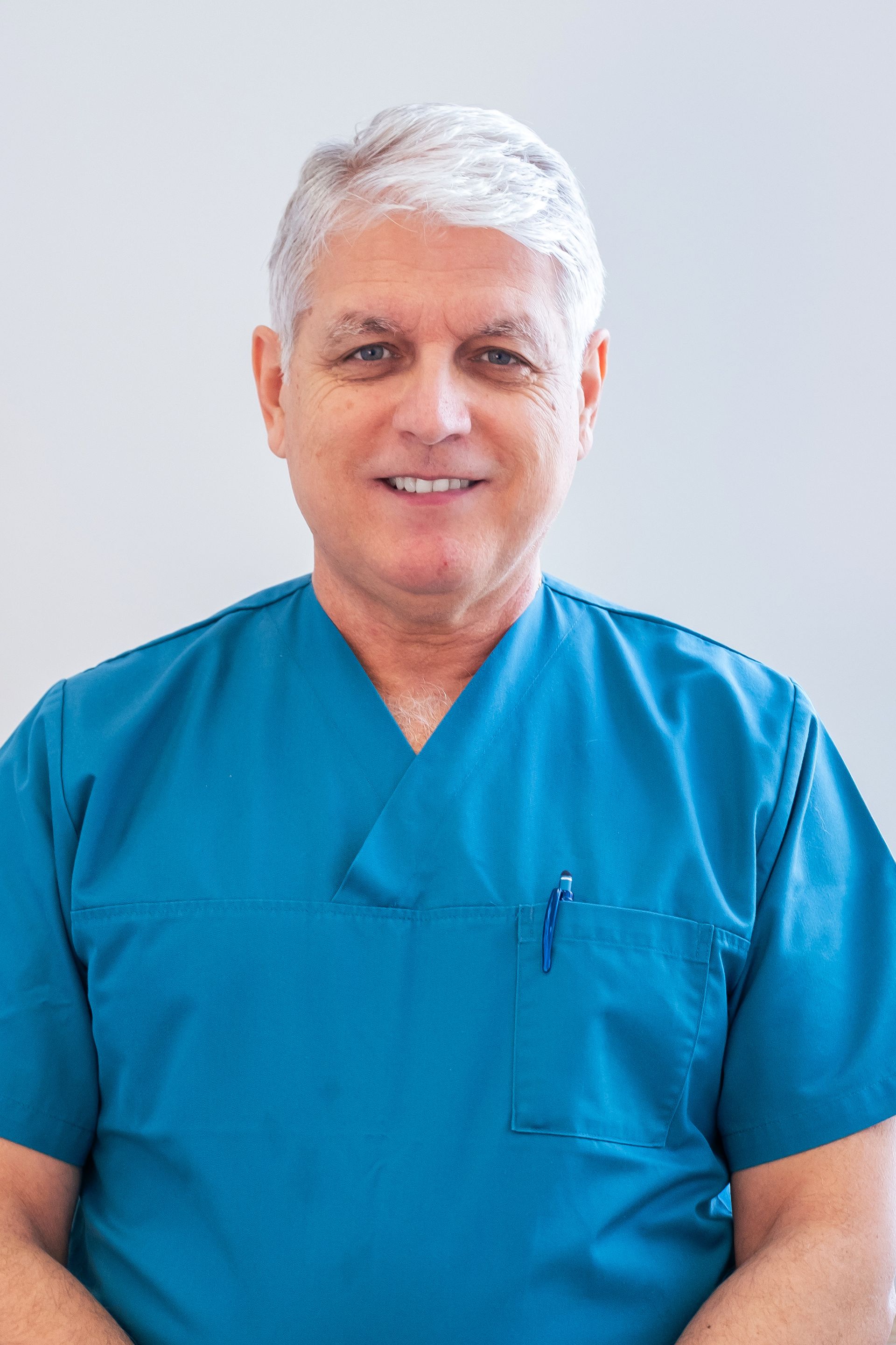 Une équipe dentaire en blouses turquoise, dirigée par le Dr Anthony Kolev, souriant dans un cabinet dentaire.