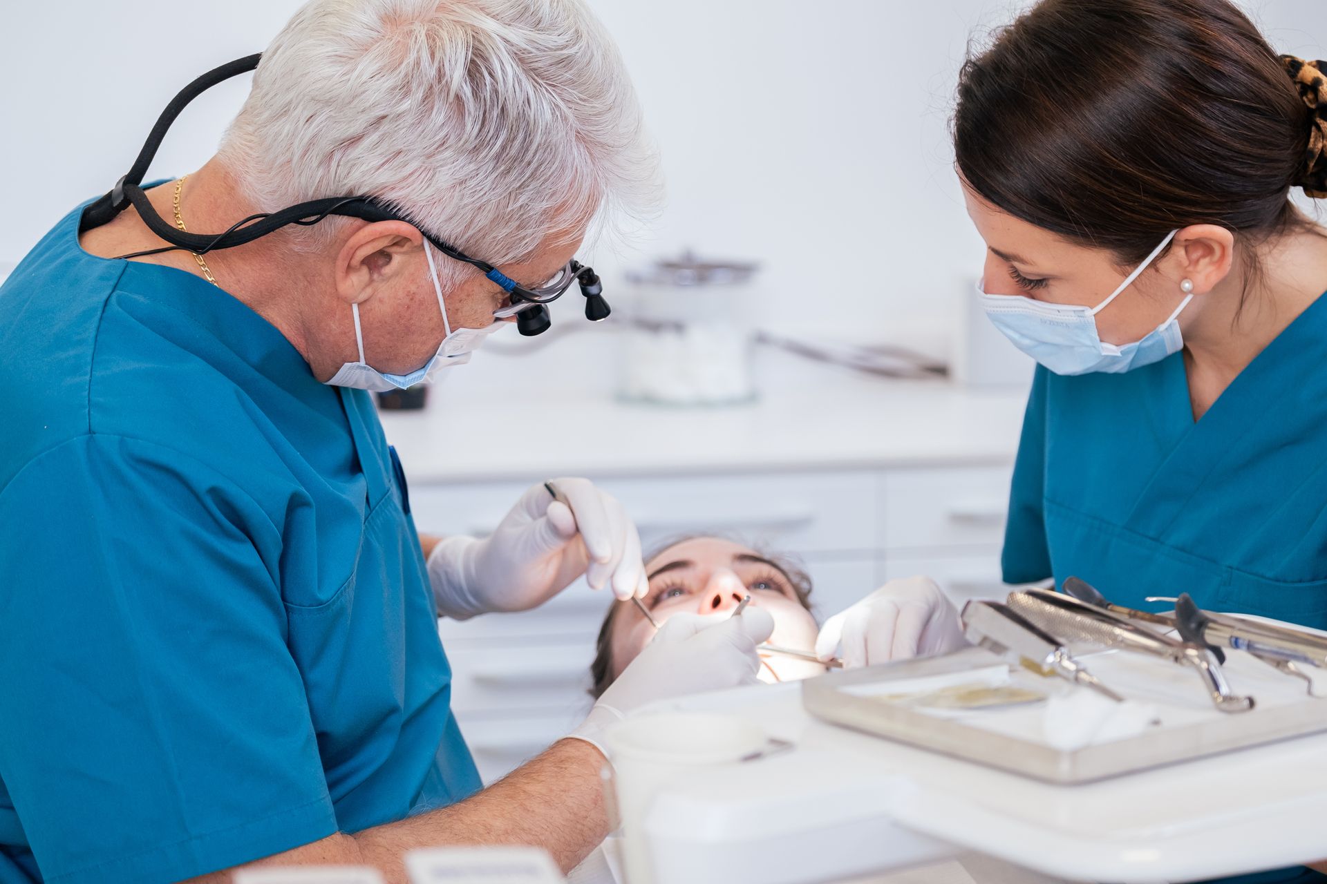 Une grande dent blanche avec un miroir dentaire devant un décor flou de cabinet dentaire.