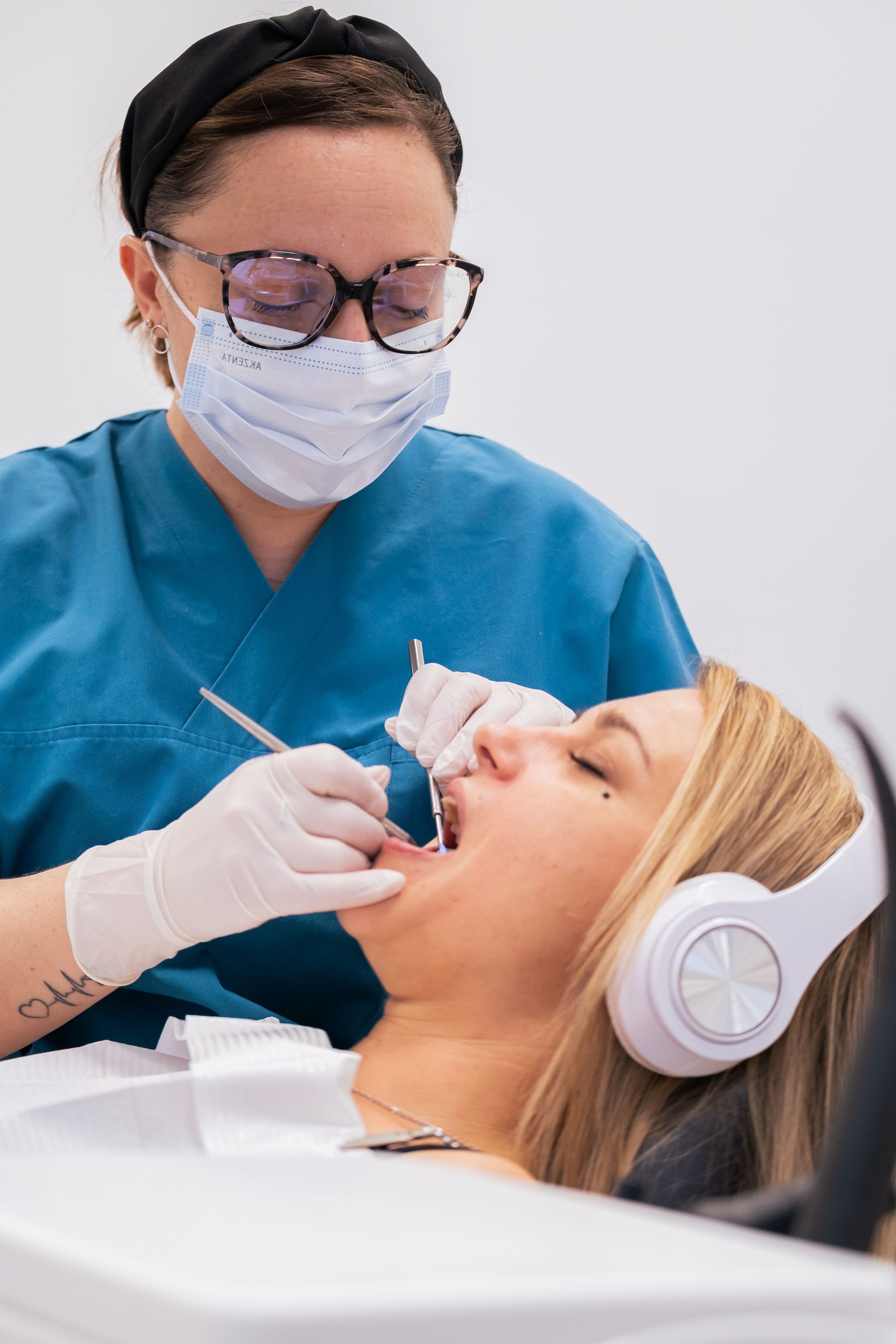 Un dentiste examine les dents blanches et éclatantes d'un patient à l'aide d'un miroir ; tous deux sourient.