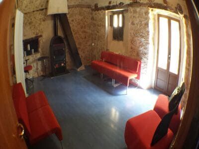 Interior acogedor con sofás rojos, paredes de piedra y estufa de leña. 