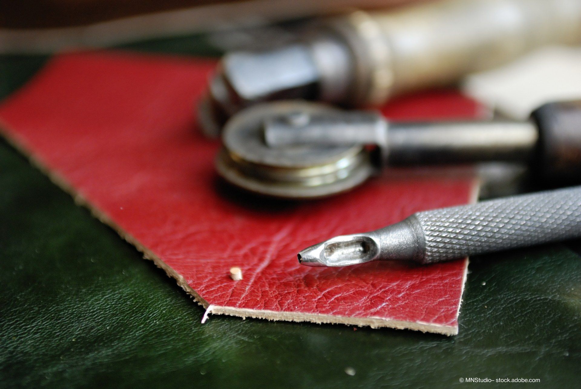 Werkzeuge einer Polsterei liegen auf einem Stück Kunstleder