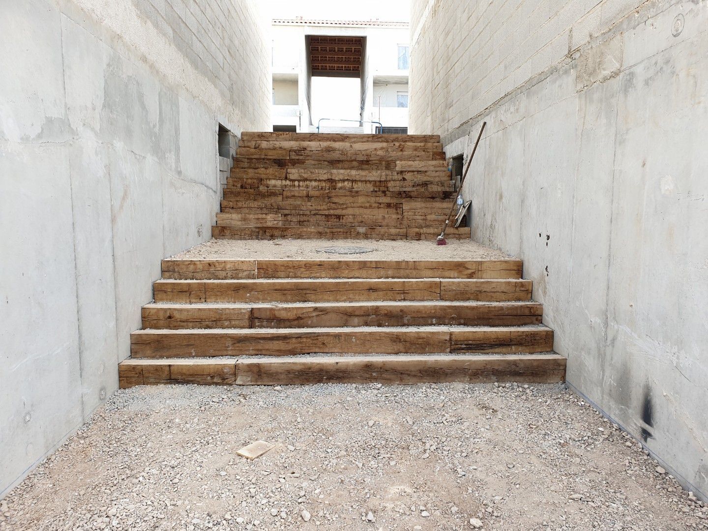 Escalier menant vers le haut à l'intérieur d'un tunnel en béton ; sol en gravier.