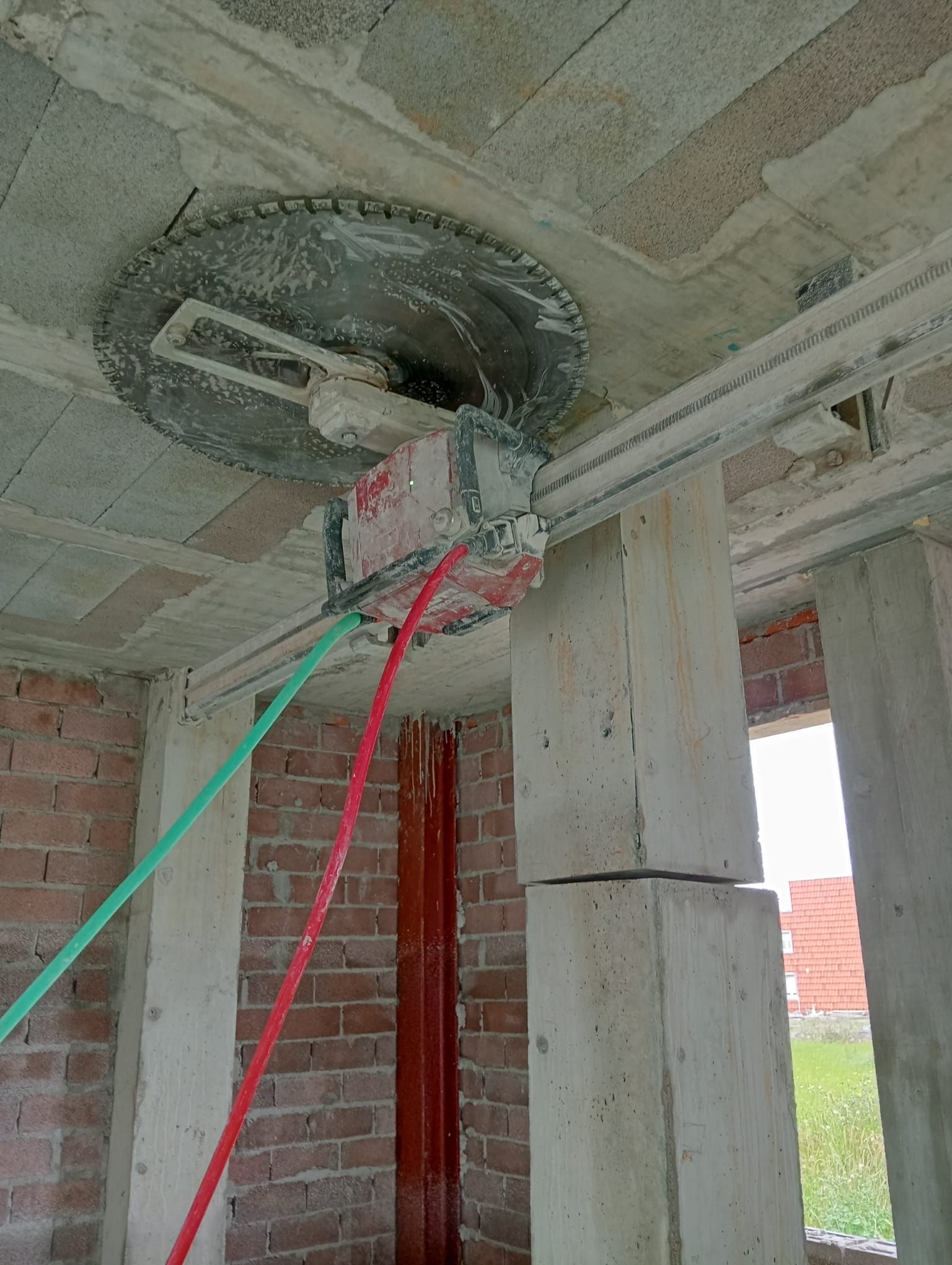 Obrero de la construcción utilizando cuerdas en una plataforma elevadora instalada en el techo de un edificio de hormigón sin terminar.