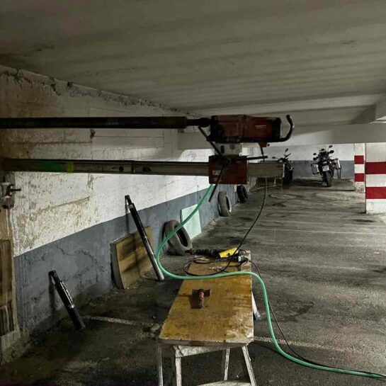 Aparcamiento subterráneo con una mesa, mangueras y maquinaria montada en la pared de hormigón.