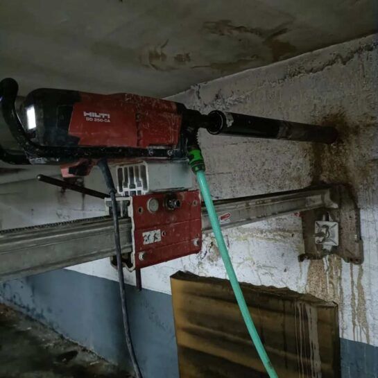 Motor rojo montado en la pared con manguera verde y tubería negra conectadas en un cuarto de servicio.