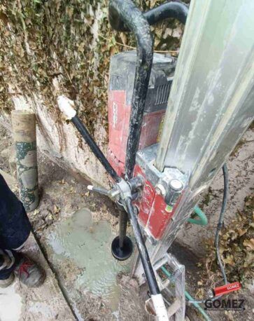Un equipo de escalada rojo y negro está sujeto al tronco de un árbol junto a un poste de metal al aire libre.