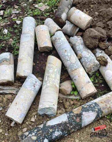 Cilindros de hormigón cubiertos de barro esparcidos por el suelo al aire libre.