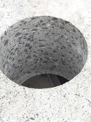 Un agujero cilíndrico gris moteado en una superficie blanca texturizada.
