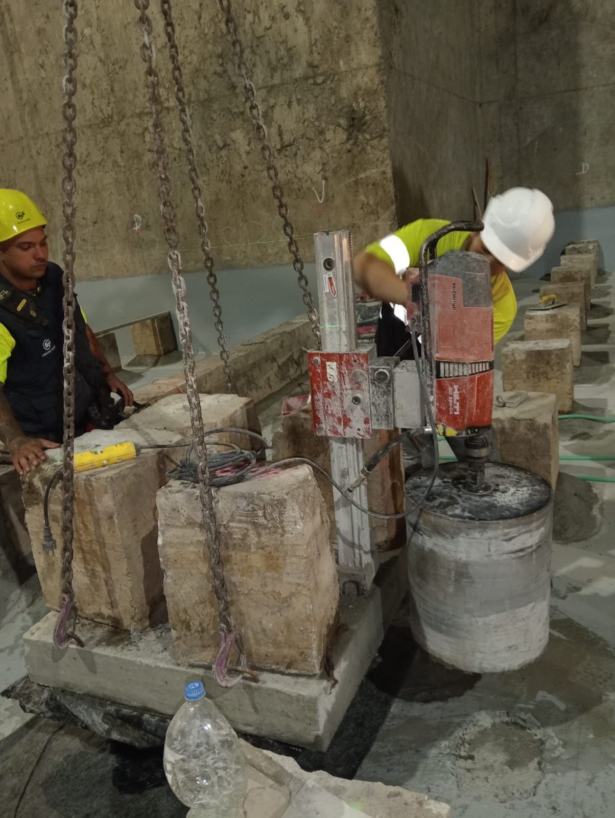 Obreros de la construcción utilizando equipos de perforación en una estructura de hormigón en una obra.