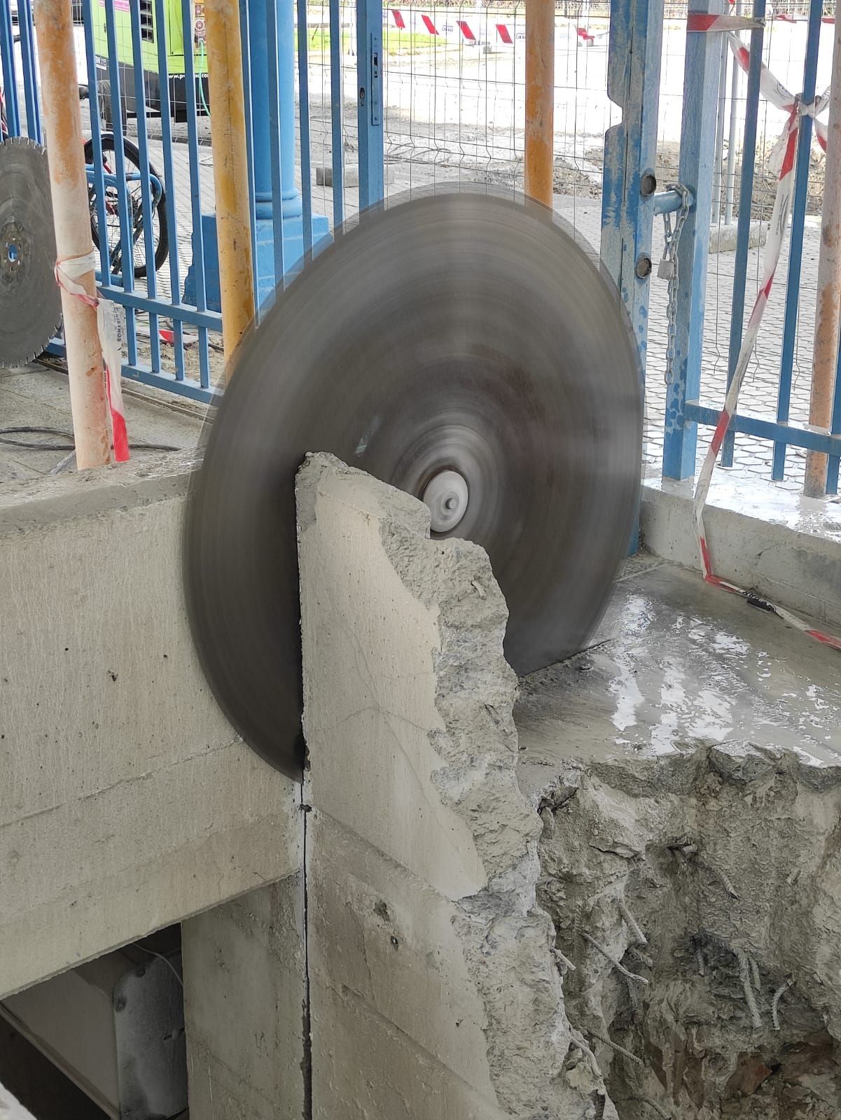 Una sierra para hormigón cortando un poste de hormigón en una obra de construcción.