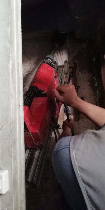 Persona trabajando en una motocicleta roja en un espacio interior estrecho.
