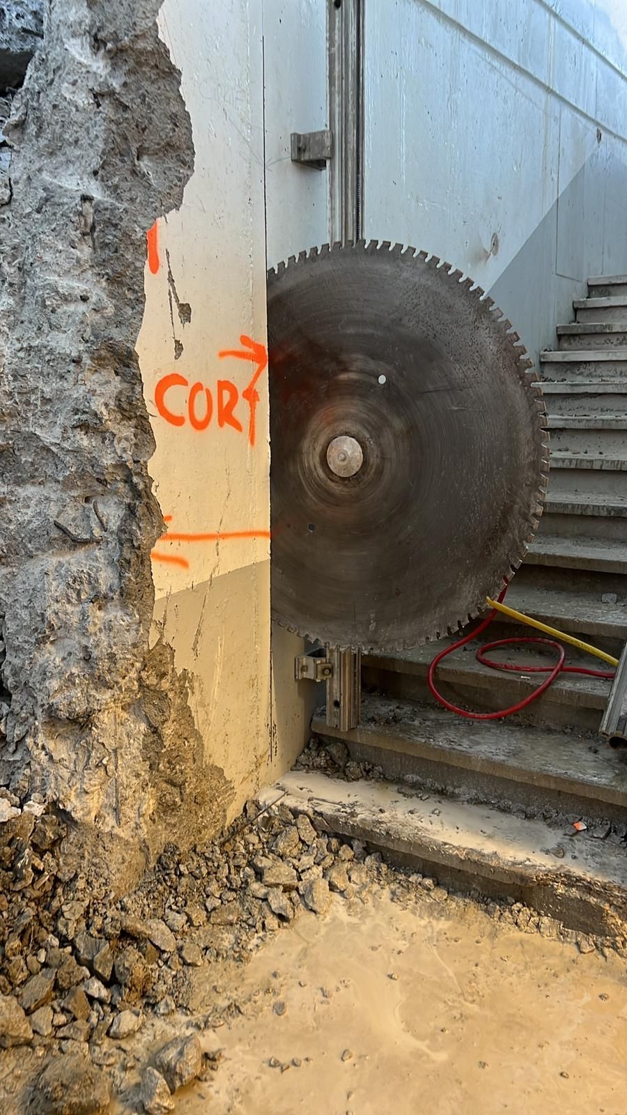 La construcción cortó la pared de hormigón cerca de las escaleras, con escombros y marcas naranjas en la pared.