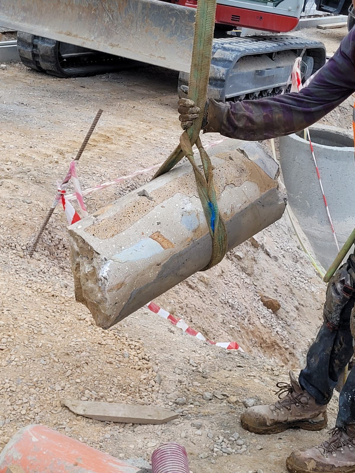 Un trabajador levanta un bloque de hormigón con una eslinga de grúa en una obra de construcción.