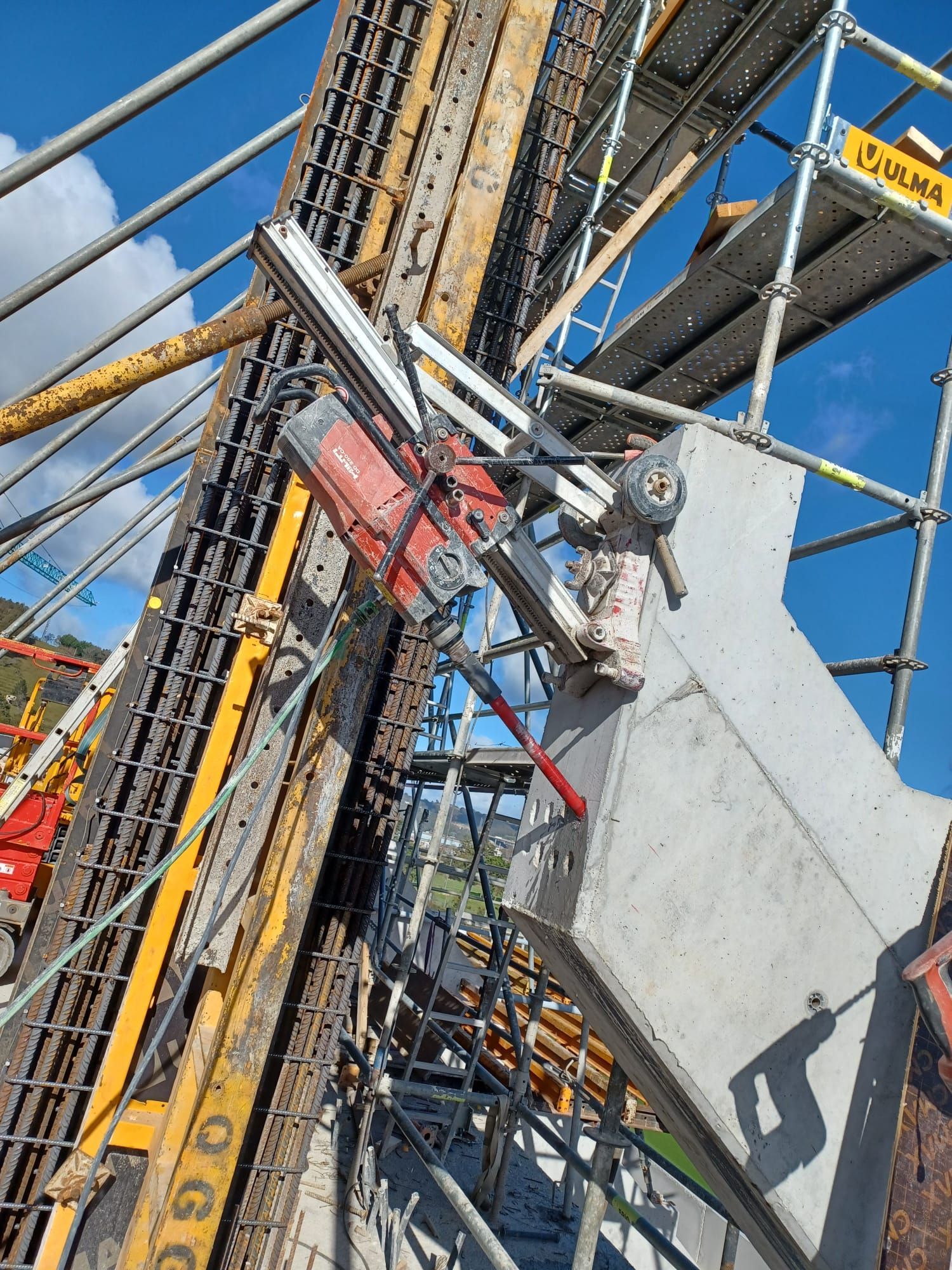 Obreros de la construcción en andamios junto a una plataforma de perforación inclinada contra un cielo azul