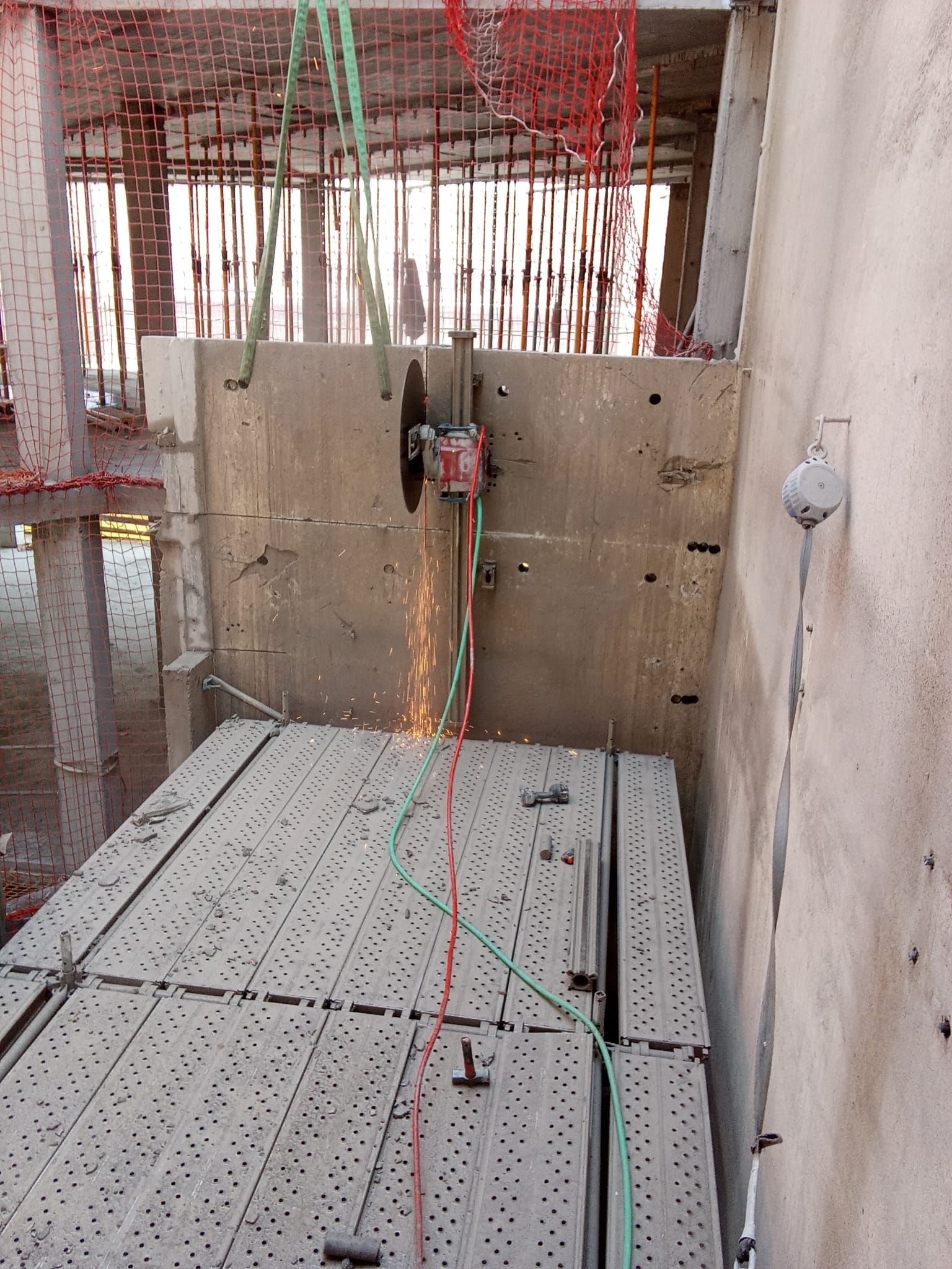 Obra en construcción con suelo de metal perforado, barras de refuerzo a la vista y encofrado de hormigón en las paredes.
