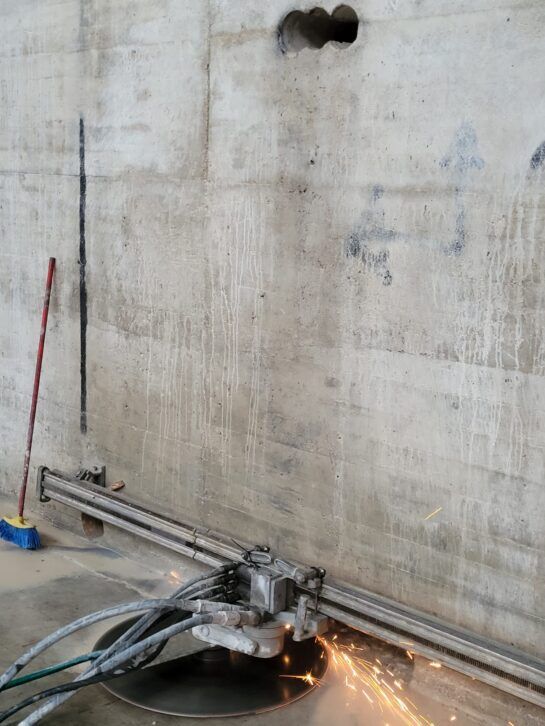 Trabajador cortando tubería de metal con chispas volando en un entorno industrial.